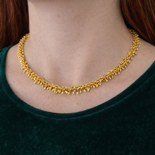 Gold necklace worn by a person with a green top