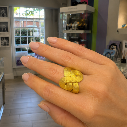 Hand wearing a 18ct gold H.Stern Celtic Dunes Statement ring inside Urban Armour Jewellery, Burnham MArket. The ring featured sweeping continuous curves and ridges and is tactile.