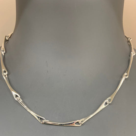 A sterling silver bracelet displayed on a mannequin torso, featuring a series of connected bone-like segments.