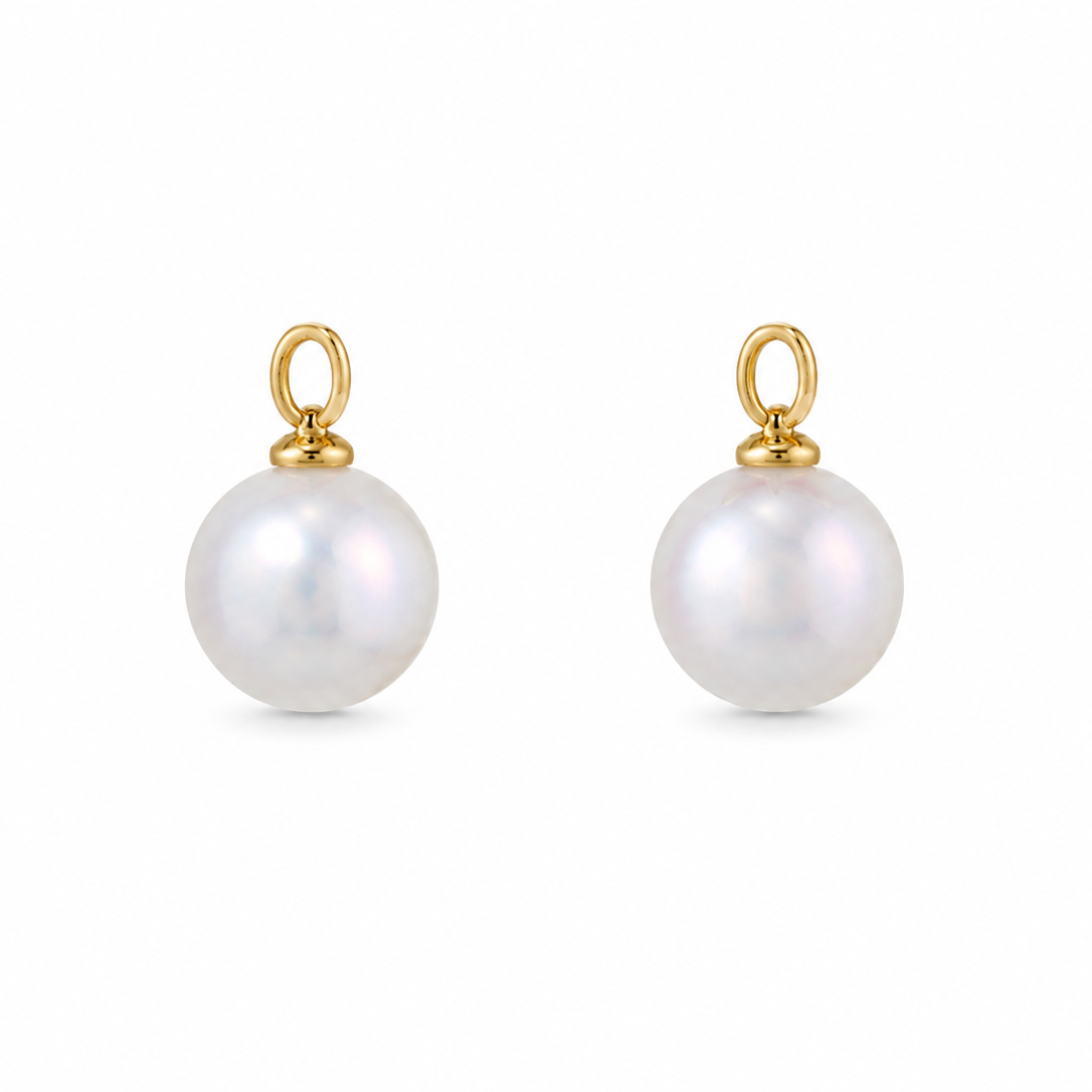 A pair of gold ear charms featuring a single round white pearl drop on each, set against a plain white background.