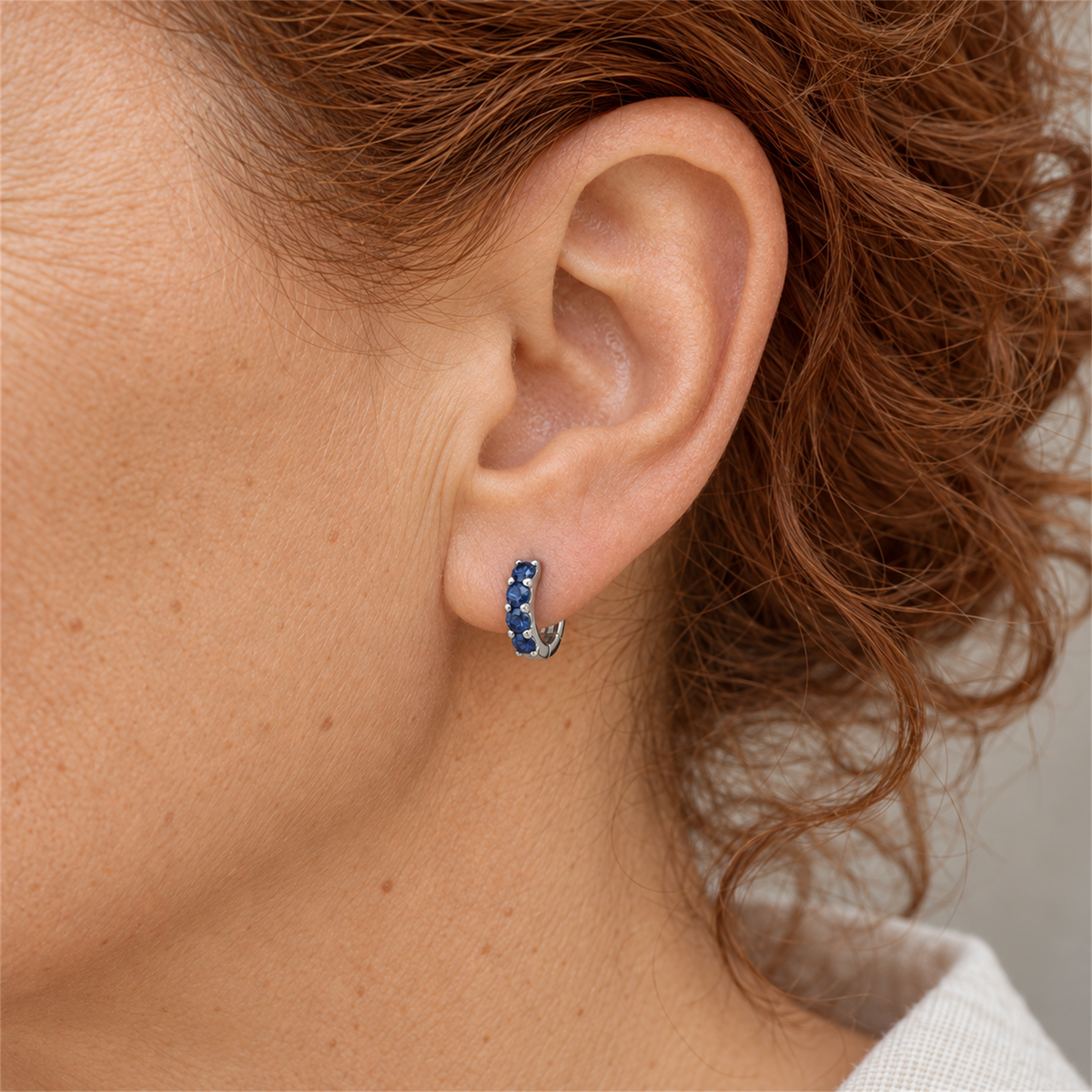 Sapphire colour cubic zirconia silver huggie earring worn by Urban Armour model