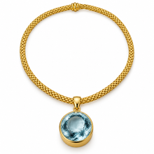 Load image into Gallery viewer, A gold mesh chain necklace with a round bezel-set light blue gemstone pendant, shown on a clean white background.

