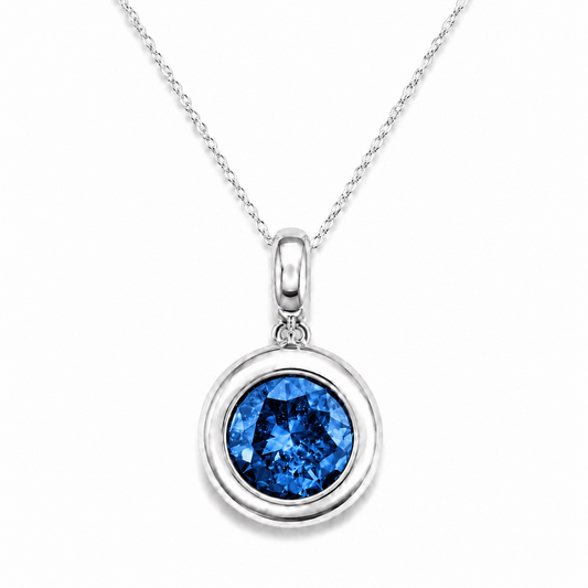 A silver pendant necklace featuring a round bezel-set blue gemstone, suspended from a delicate silver chain against a clean white background.