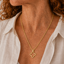 Load image into Gallery viewer, A close-up of a woman wearing a delicate gold chain necklace with a small open quatrefoil pendant, styled with a white linen shirt.
