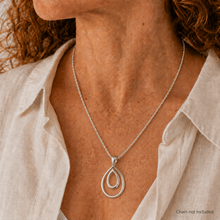 Load image into Gallery viewer, A close-up of a woman wearing a silver double teardrop pendant necklace with a silver chain, styled with a light beige linen shirt. The text 'Chain not included' is visible in the bottom right corner.
